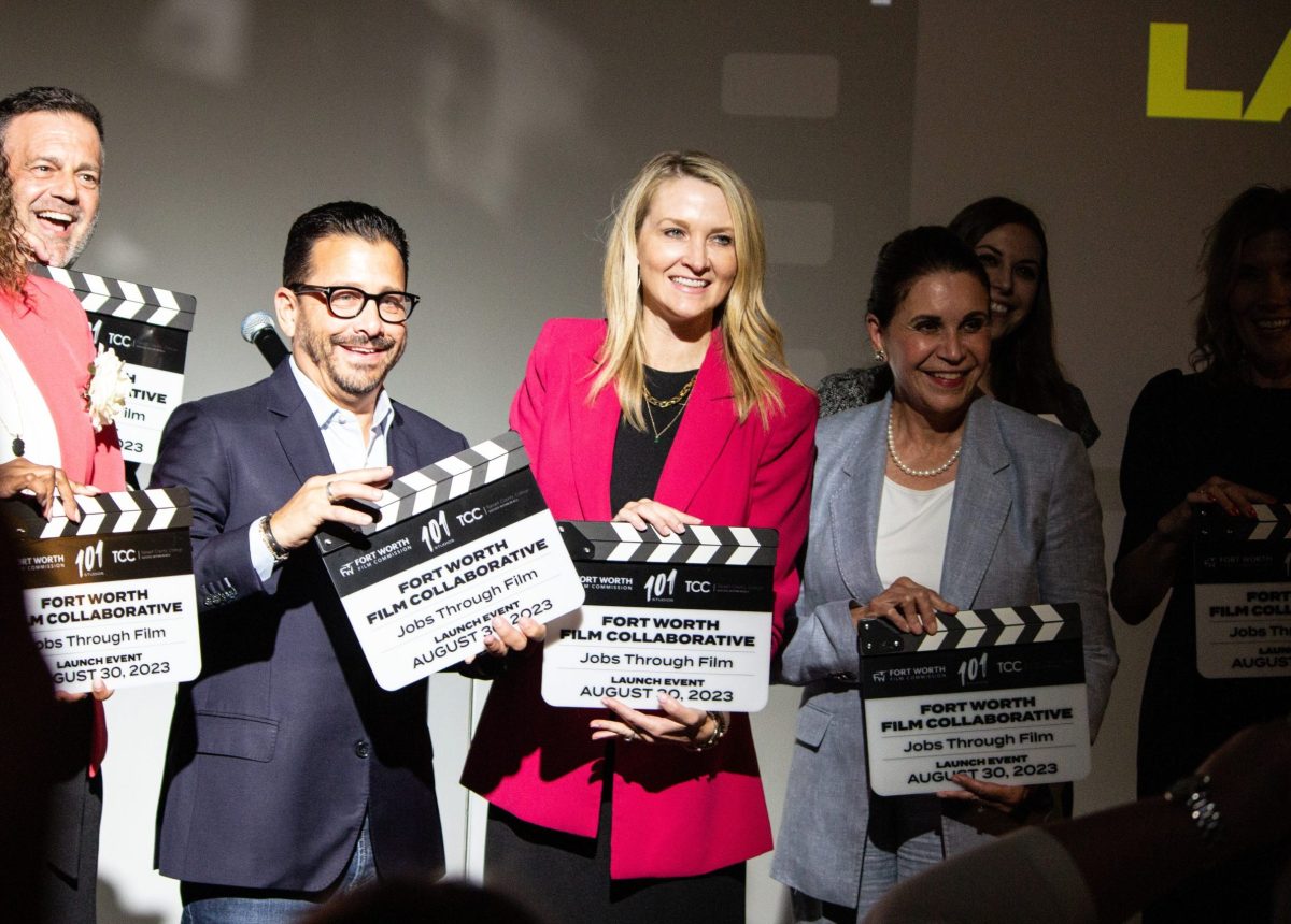 A group of people stand under the spotlight with film clappers