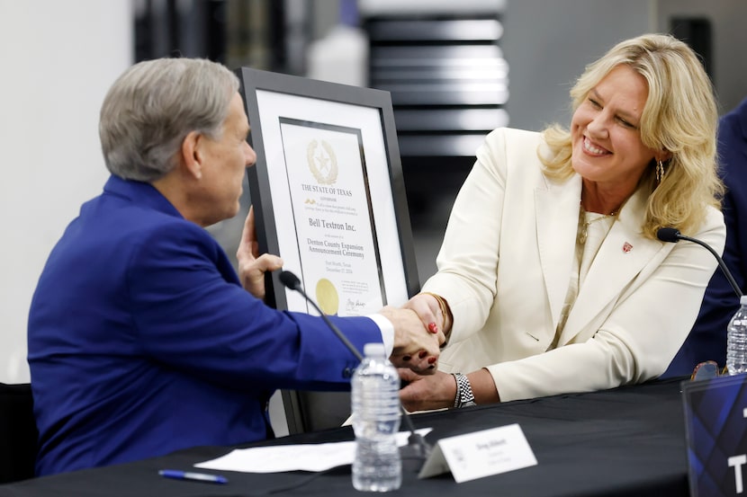 Texas Gov. Greg Abbott (left) hands a certificate and shakes hands with Bell Textron CEO...